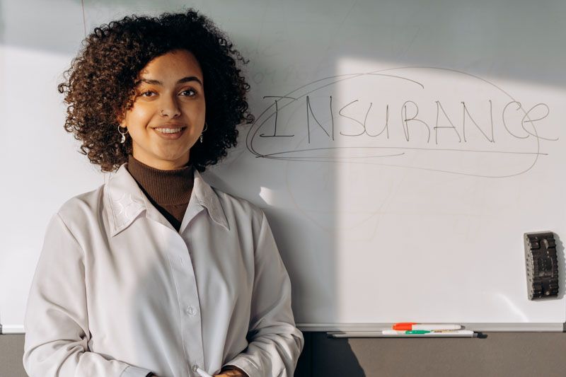 Woman next to "insurance" written on a white board